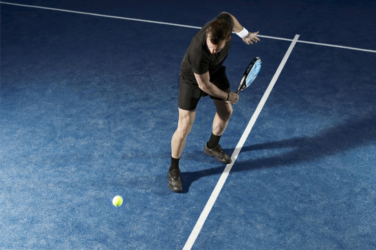 Padel-Spieler in Aktion auf blauem Padelplatz