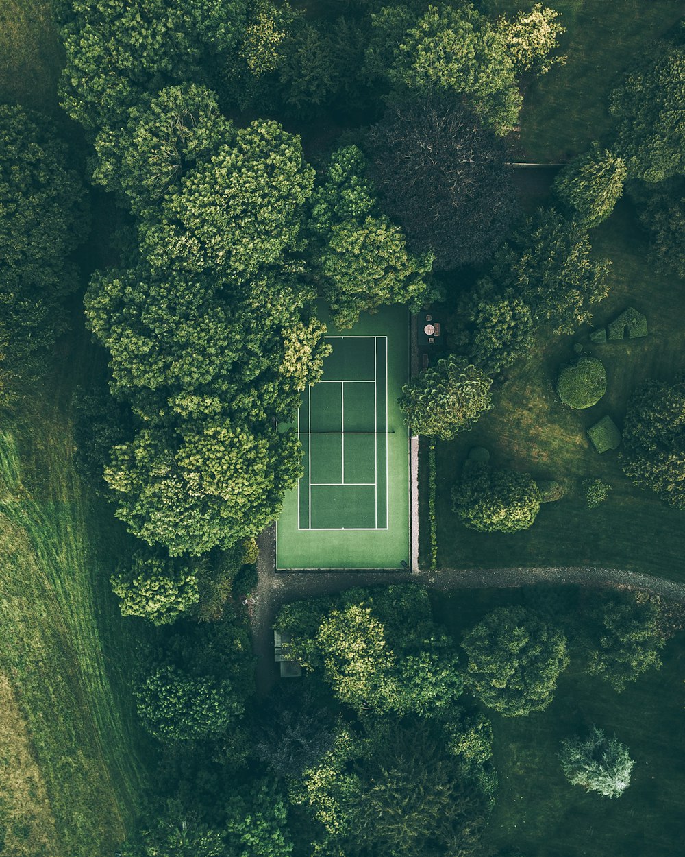 Tennisplatz von oben, eingebettet in Grün